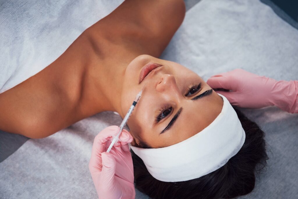 Woman that lying down in spa salon and have injection by the syringe into her face skin